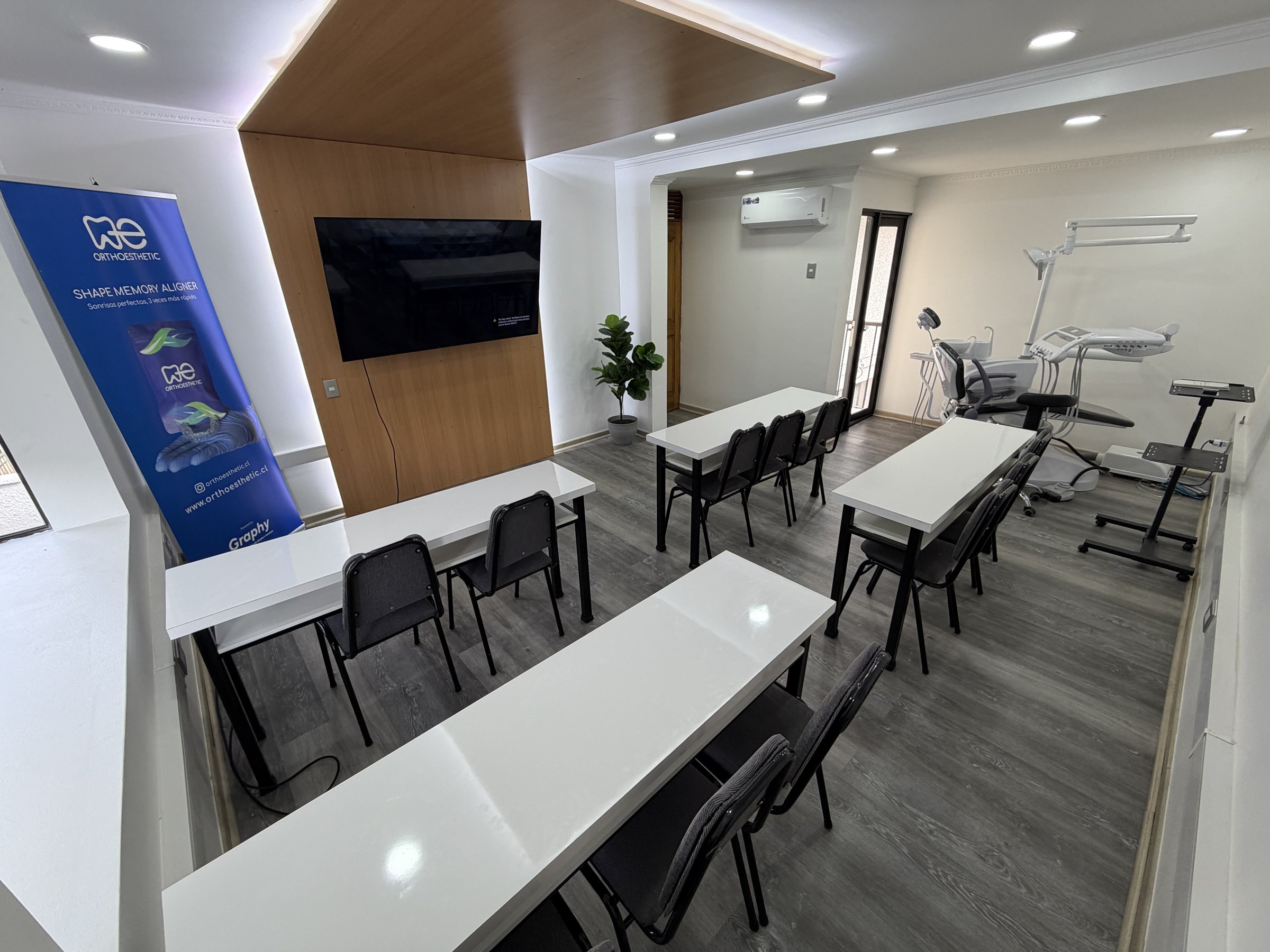 Mesas para 15 personas con pantalla y sillón dental al fondo