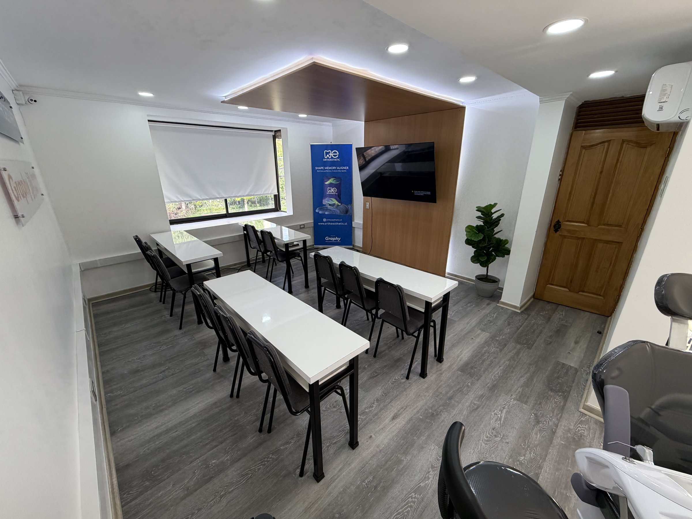 Sala de capacitación con mesas, ventana y pantalla